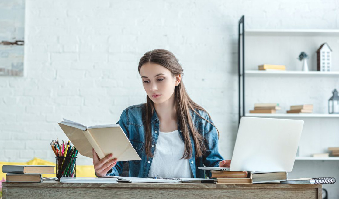 Ілюстрація: дівчина з книжкою за ноутбуком