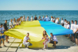 фото молоді з українським прапором (полотном) в руках на березі моря на Миколіївщині
