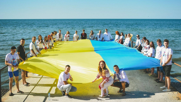 фото молоді з українським прапором (полотном) в руках на березі моря на Миколіївщині